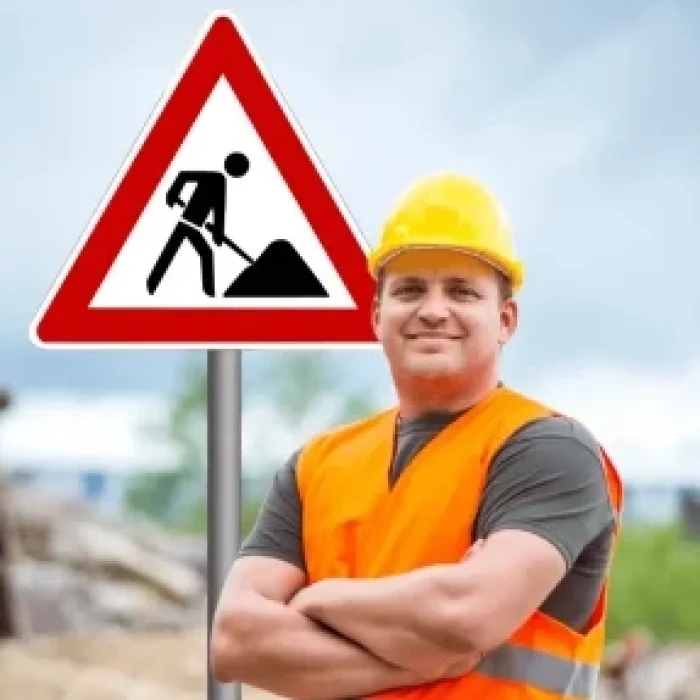 Mitarbeiter mit Warnweste vor Baustellenschild als symbolisches Bild für eine RSA 21 Online Schulung zur Baustellensicherung.